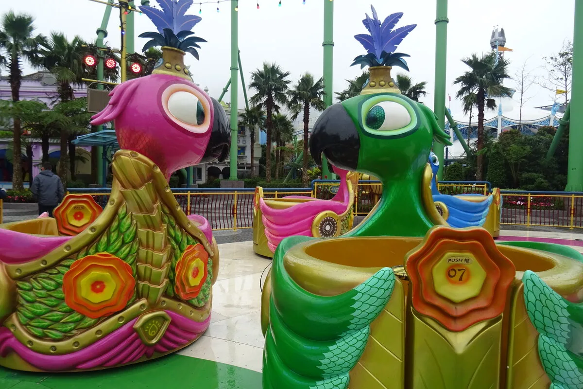 Colourful parrot-shaped spinning ride cars in the Rio zone of Genting SkyWorlds