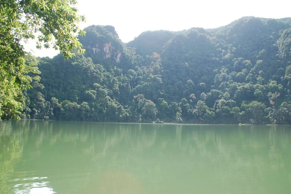 Calm green waters of the Pregnant Maiden Lake ringed by jungle-clad karst cliffs