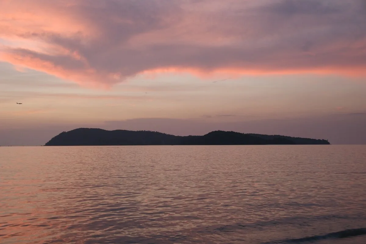 Pink sunset sky over calm sea and an island silhouette off Langkawi