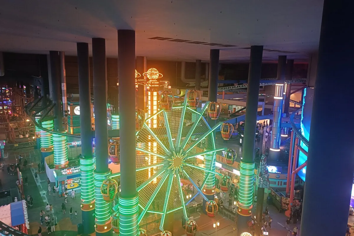 Neon-lit Ferris wheel and rides seen from above at Skytropolis Indoor Theme Park, Genting