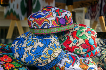 Traditional colorful embroidered hats displayed at a local market in Almaty, Kazakhstan, showcasing intricate patterns and vibrant cultural designs.