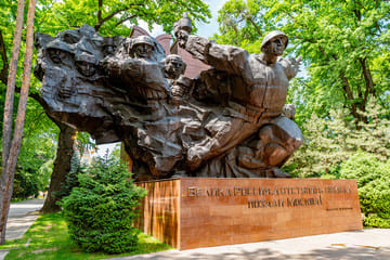 Statue of the Panfilov Heroes in Almaty’s Panfilov Park, commemorating soldiers who defended Moscow during World War II, surrounded by lush greenery