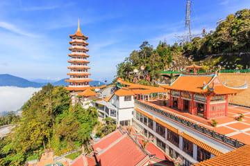 A panoramic view of Genting Highlands, showcasing the iconic Chin Swee Caves Temple with its traditional pagoda, surrounded by lush greenery and mountain vistas.