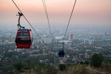 Scenic view of cable cars ascending Kok Tobe Hill Almaty at sunset, with panoramic city views and mountains in the background, highlighting the iconic attraction of Kazakhstan."
