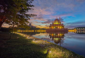A breathtaking night view of a dome reflecting in tranquil waters, illuminated with soft lights, showcasing architectural beauty and serenity in Putrajaya, Malaysia.