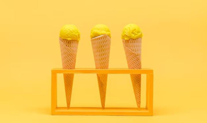 Avibrant yellow backdrop with three colorful soft-serve ice cream cones in the foreground, showcasing the delightful 'Tasting Galore of Ice Cream' experience.
