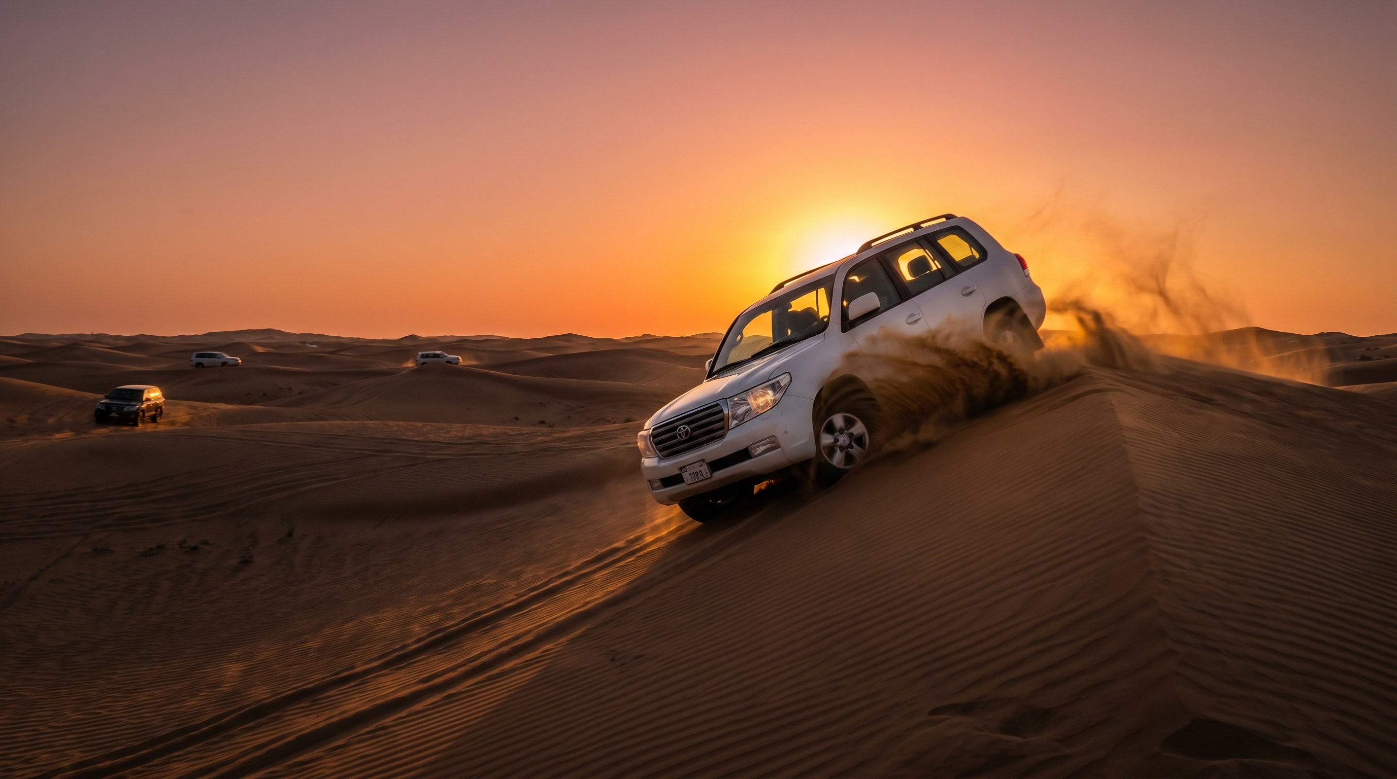 A 4x4 cresting a sand dune at sunset on a Dubai desert safari