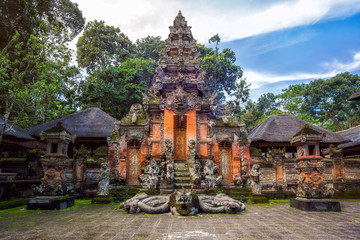 Statue-filled entrance to Ubud Monkey Forest Bali, showcasing intricately carved Balinese architecture surrounded by lush greenery and monkeys exploring their natural habitat.