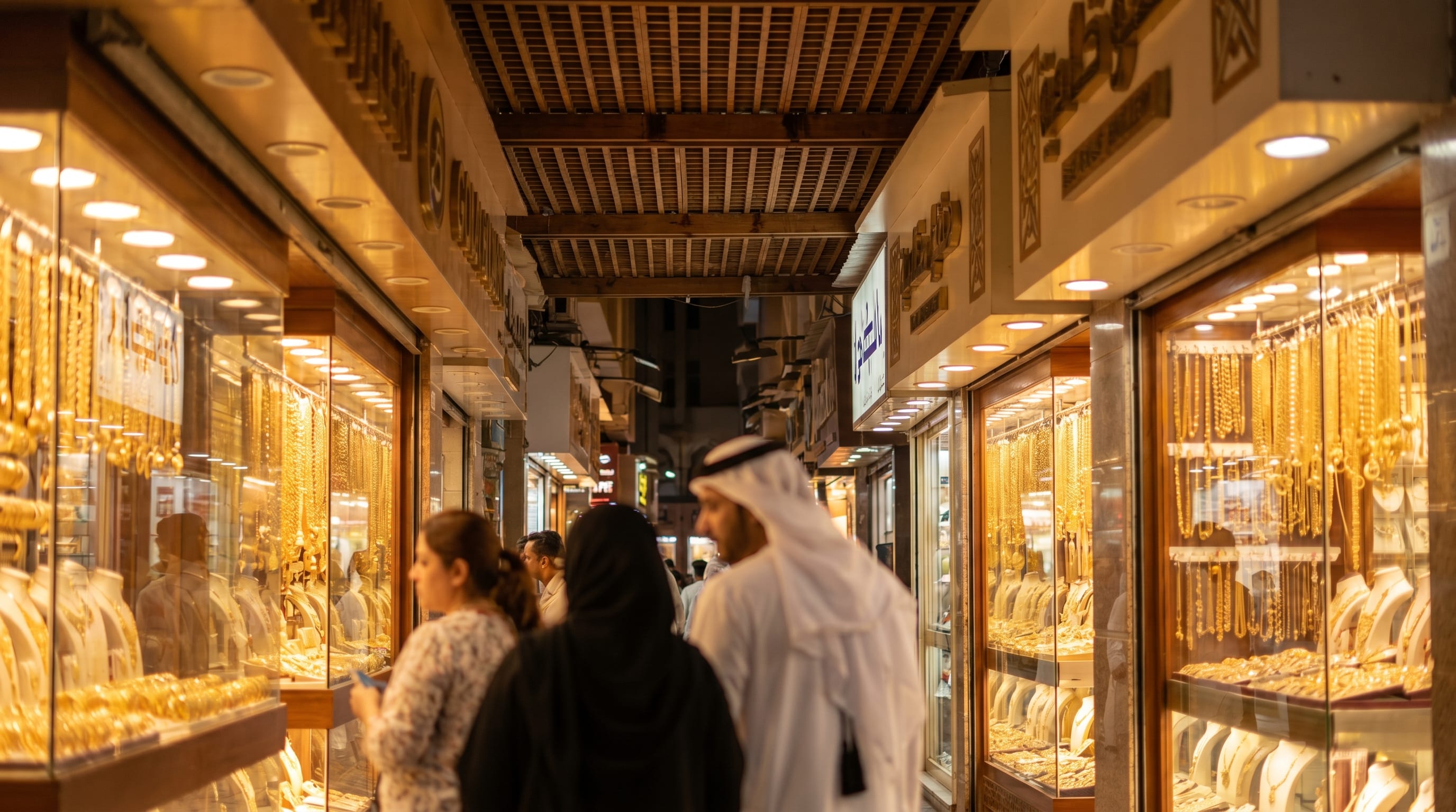 Shopping in Dubai gold souk shopfronts glowing at night in Deira