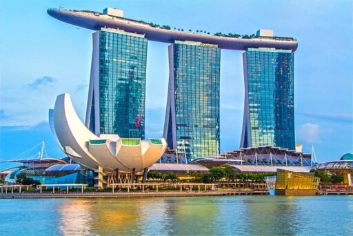 Night view of Marina Bay Sands and Helix Bridge in Singapore, illuminated with vibrant lights reflecting on the water. Best Time to visit Singapore