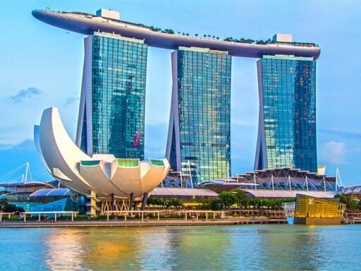 Night view of Marina Bay Sands and Helix Bridge in Singapore, illuminated with vibrant lights reflecting on the water. Best Time to visit Singapore