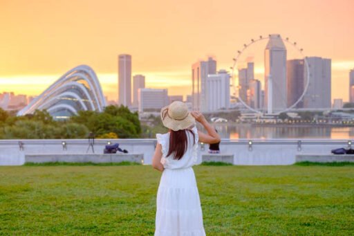 A girl is standing wearing a white costume and hat watching towards Singapore city. Best Hidden Gems to Explore in Singapore