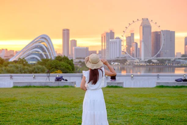 A girl is standing wearing a white costume and hat watching towards Singapore city. Best Hidden Gems to Explore in Singapore