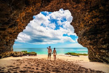 A stunning view of one of Bali's hidden beaches, featuring a natural rock archway framing the ocean with turquoise waters and soft sand. Perfect for a peaceful getaway and part of the Top 10 Hidden Beaches of Bali.