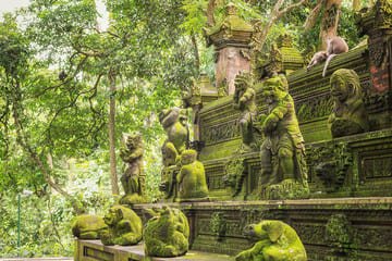 Ubud Monkey Forest Bali: Ancient moss-covered stone sculptures surrounded by lush greenery and playful long-tailed macaques in their natural habitat, showcasing the spiritual and cultural essence of this iconic Balinese sanctuary.