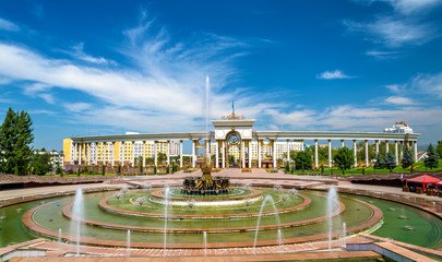 Majestic view of a fountain in front of the Presidential Park in Almaty, Kazakhstan, surrounded by grand architecture and lush greenery, representing the cultural charm included in the Almaty Travel Package.