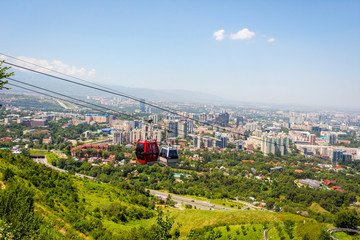 A stunning view from the Kok-Tobe cable car, with the city skyline below and the snow-capped mountains in the background, offering a memorable and scenic ride to one of Almaty's top attractions.