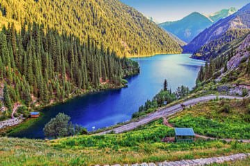 Stunning view of Big Almaty Lake surrounded by lush greenery and snow-capped mountains, highlighting Almaty's natural beauty.