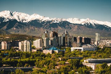 A scenic view of Almaty, Kazakhstan, showcasing the city skyline against the backdrop of the snow-capped Tian Shan Mountains, highlighting the natural beauty and urban charm included in the Almaty Travel Package.