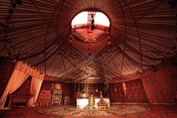 Interior view of a traditional Kazakh yurt in Alma-Ata, beautifully adorned with intricate patterns, vibrant textiles, and cultural artifacts showcasing nomadic heritage.