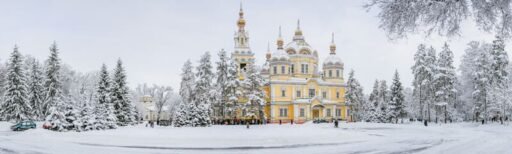 Panoramic view of the Ascension Cathedral surrounded by snow-covered trees in Almaty's Panfilov Park, capturing the essence of Almaty tour vibes with its blend of culture and winter beauty