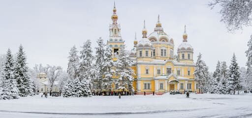 Panoramic view of the Ascension Cathedral surrounded by snow-covered trees in Almaty's Panfilov Park, capturing the essence of Almaty tour vibes with its blend of culture and winter beauty