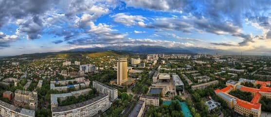 A breathtaking panoramic view of Almaty, Kazakhstan, showcasing the city's urban architecture, lush greenery, and the majestic Tian Shan Mountains in the background. Perfect for travelers exploring Almaty's rich culture, history, and natural beauty. Keywords: Travel to Almaty Kazakhstan.