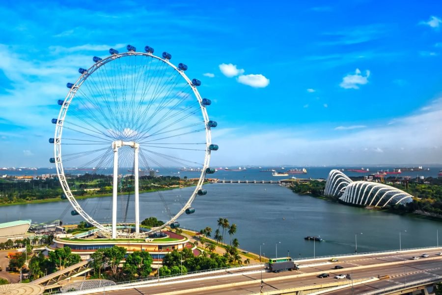 A breathtaking view of the Singapore Flyer, one of the world's largest observation wheels, overlooking Marina Bay with the stunning Gardens by the Bay in the background.